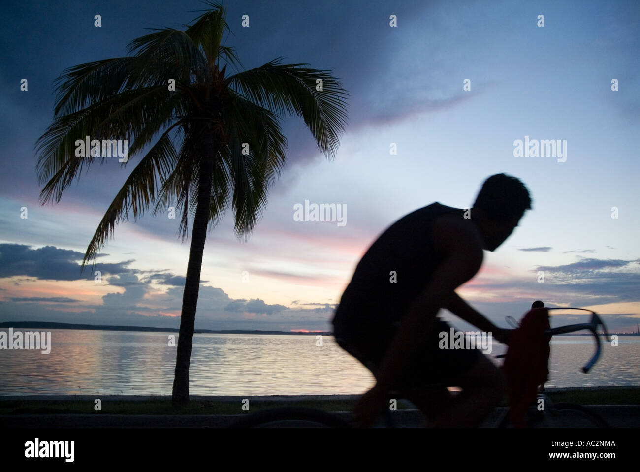 Mann, Radfahren entlang der Küste bei Sonnenuntergang, Cienfuegos, Kuba. Stockfoto