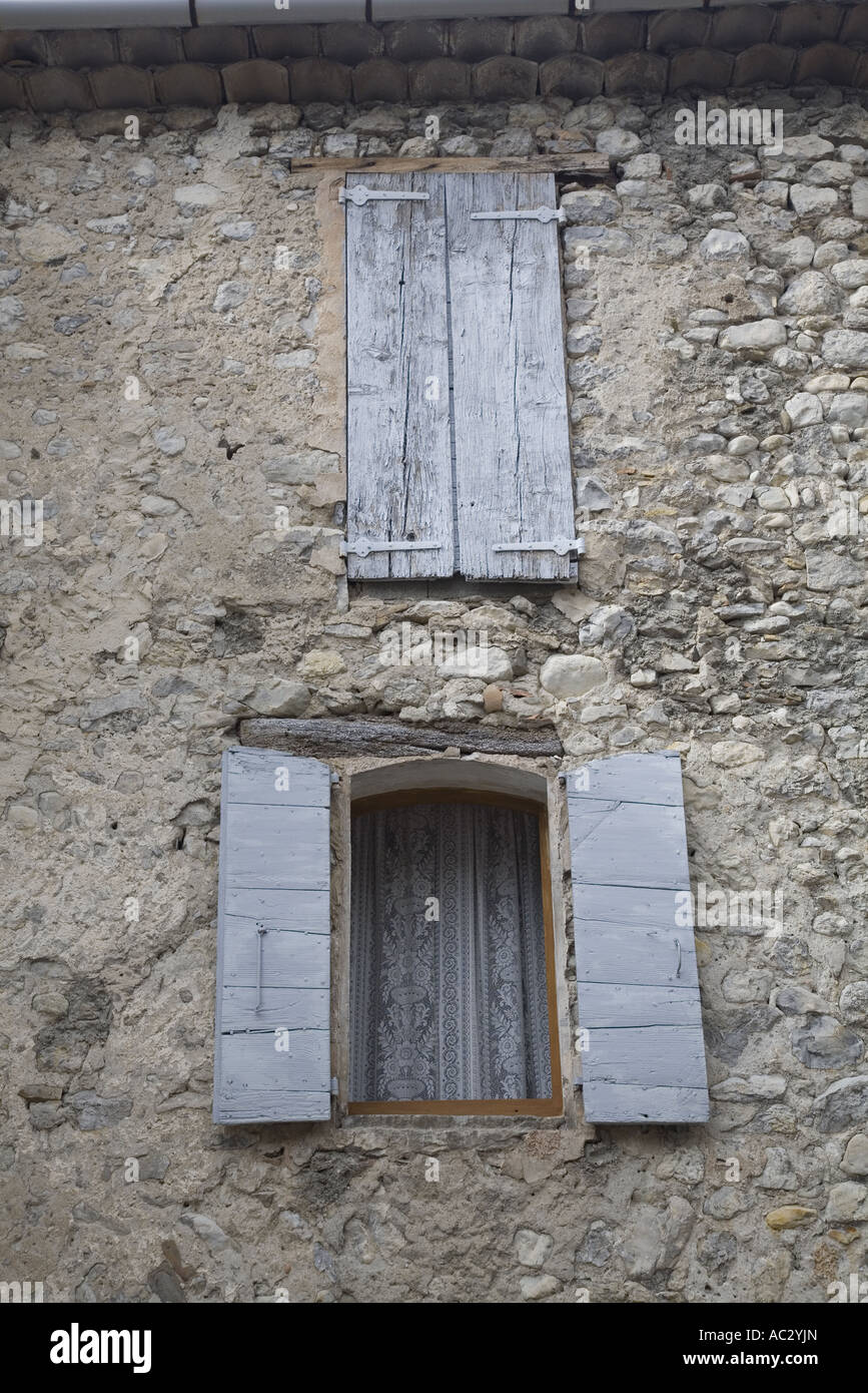 Ein offenes und ein geschlossenes Fenster mit verwitterten Fensterläden in einem alten Haus in Rémuzat, Drôme, Frankreich Stockfoto