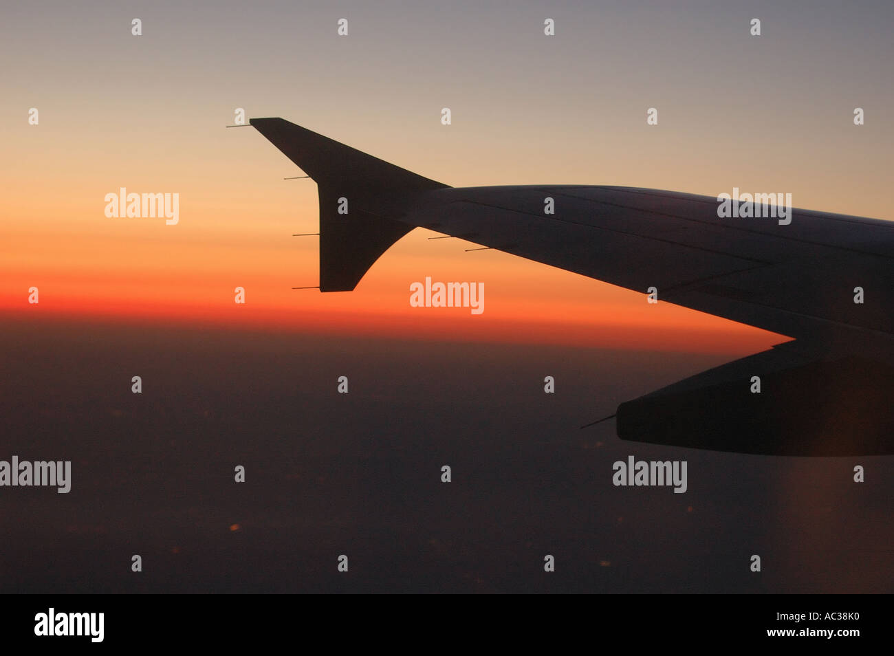 Ein Flügel in einem Flugzeug ist als die Sonnenuntergänge, während Sie auf dem Weg zu ihrem Bestimmungsort Silhouette. Stockfoto