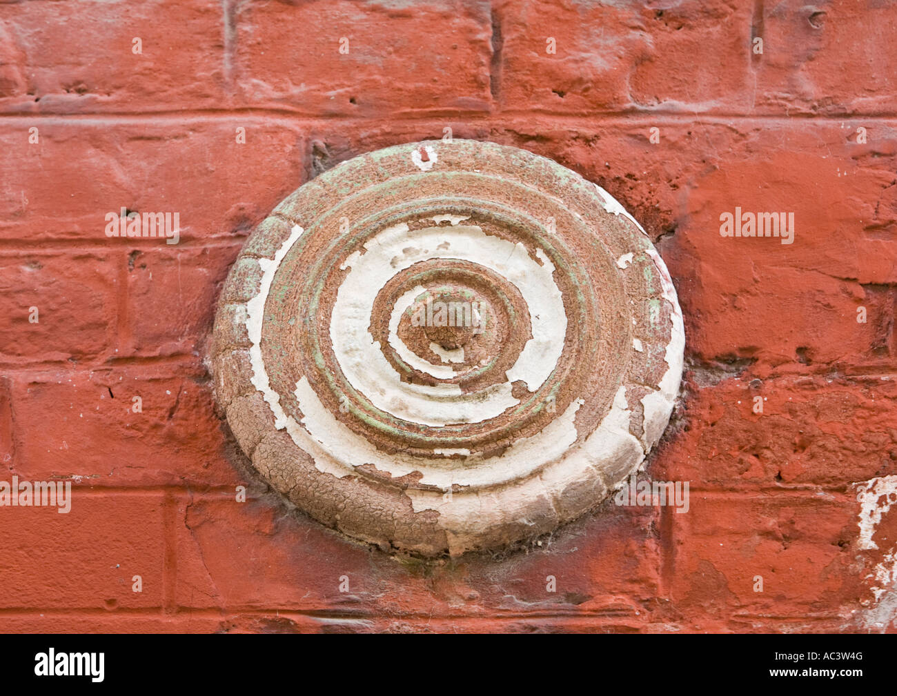 Weiße runde Platte am rot bemalten Mauer Krawatte Stockfoto