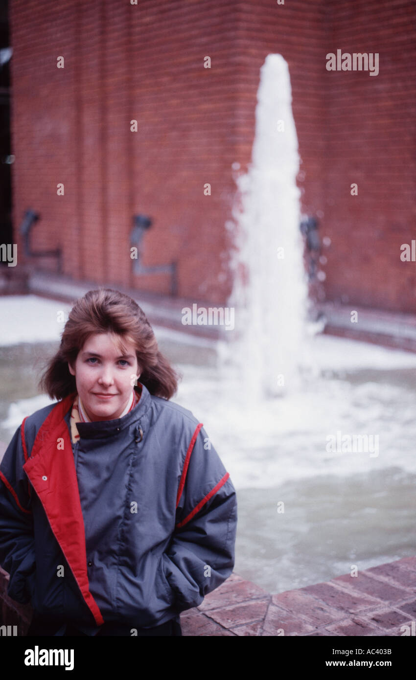 Porträt einer jungen Frau aus den 1980er Jahren in einen Anorak vor einem Brunnen Stockfoto