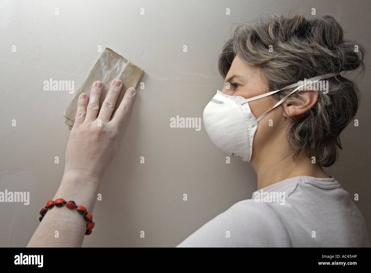 Eine junge Frau Abschleifen des Putzes von einer Wand (Frankreich).  Jeune Femme Ponçant un Mur Recouvert de Plâtre (Frankreich). Stockfoto