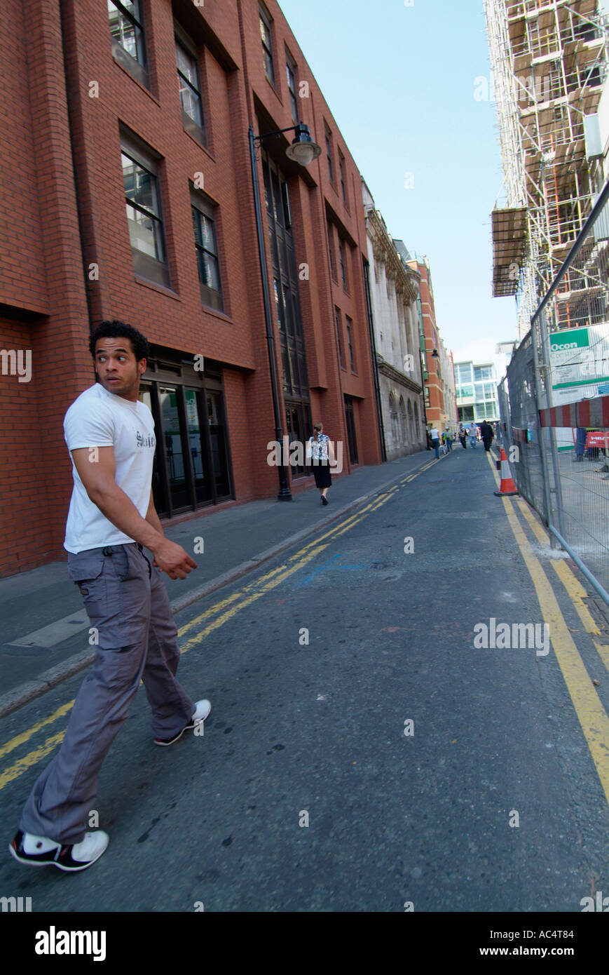 Junger Mann auf der Suche über die Schulter zu Manchester City Centre GB UK EU Europa weglaufen Stockfoto