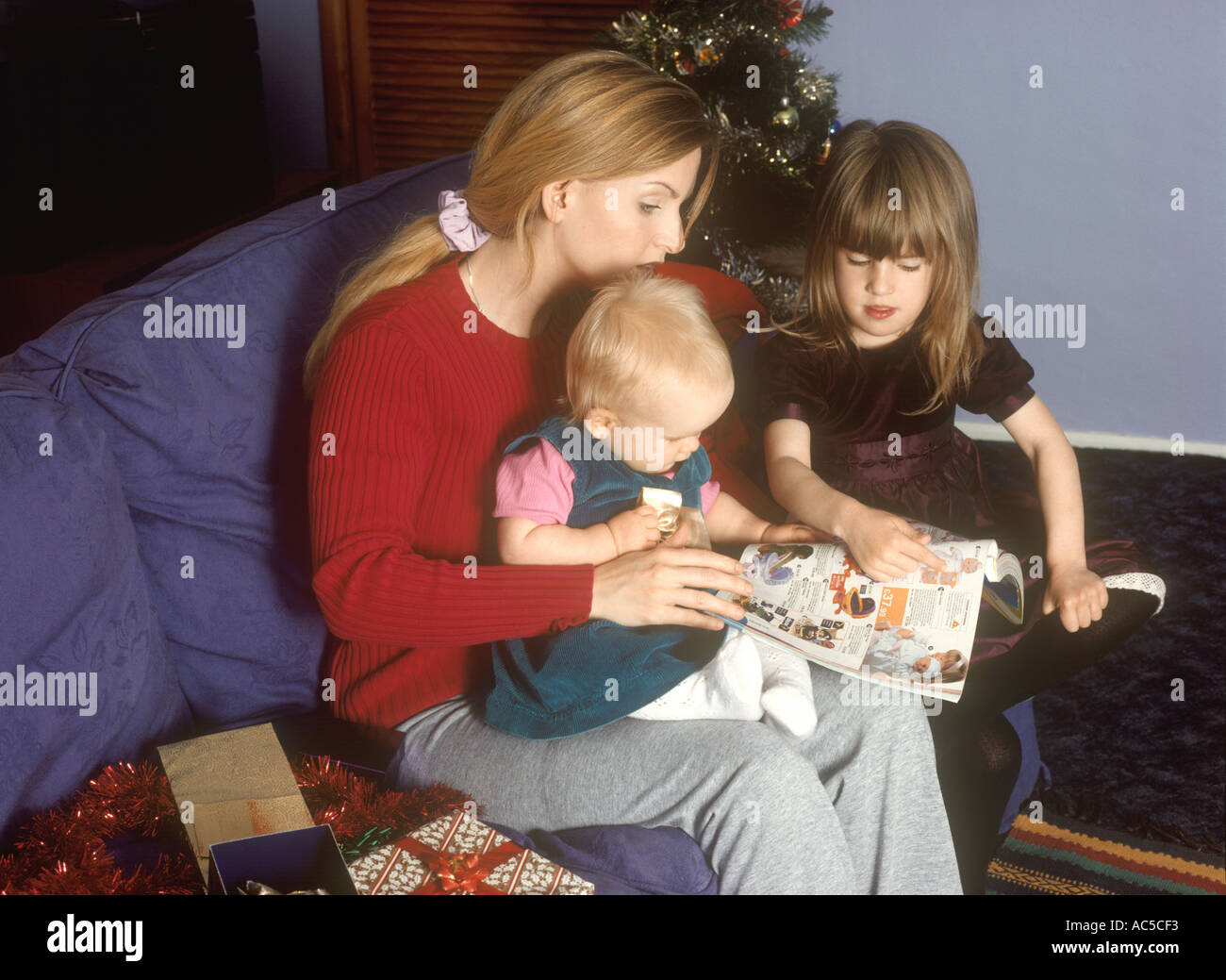 Mutter mit ihren Kindern auf der Suche in einem Katalog für Spielzeug und Geschenke, belästigt zu werden Stockfoto