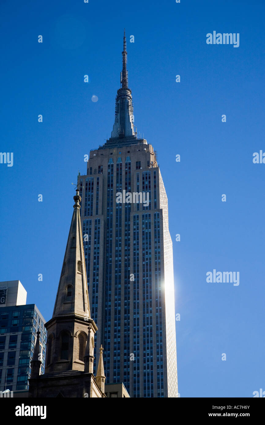 Empire State Building und Teil der Trinity Church in Frühling Sonne Sonnenschein mit blauem Himmel Downtown Manhattan New York City New York NYC Stockfoto