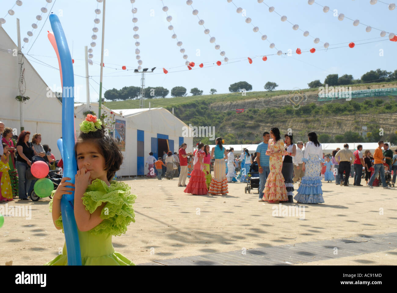 Junges Mädchen in traditionellen Flamenco-Kleid hält lange Luftballons in Vejer Feria, Andalusien, Spanien Stockfoto