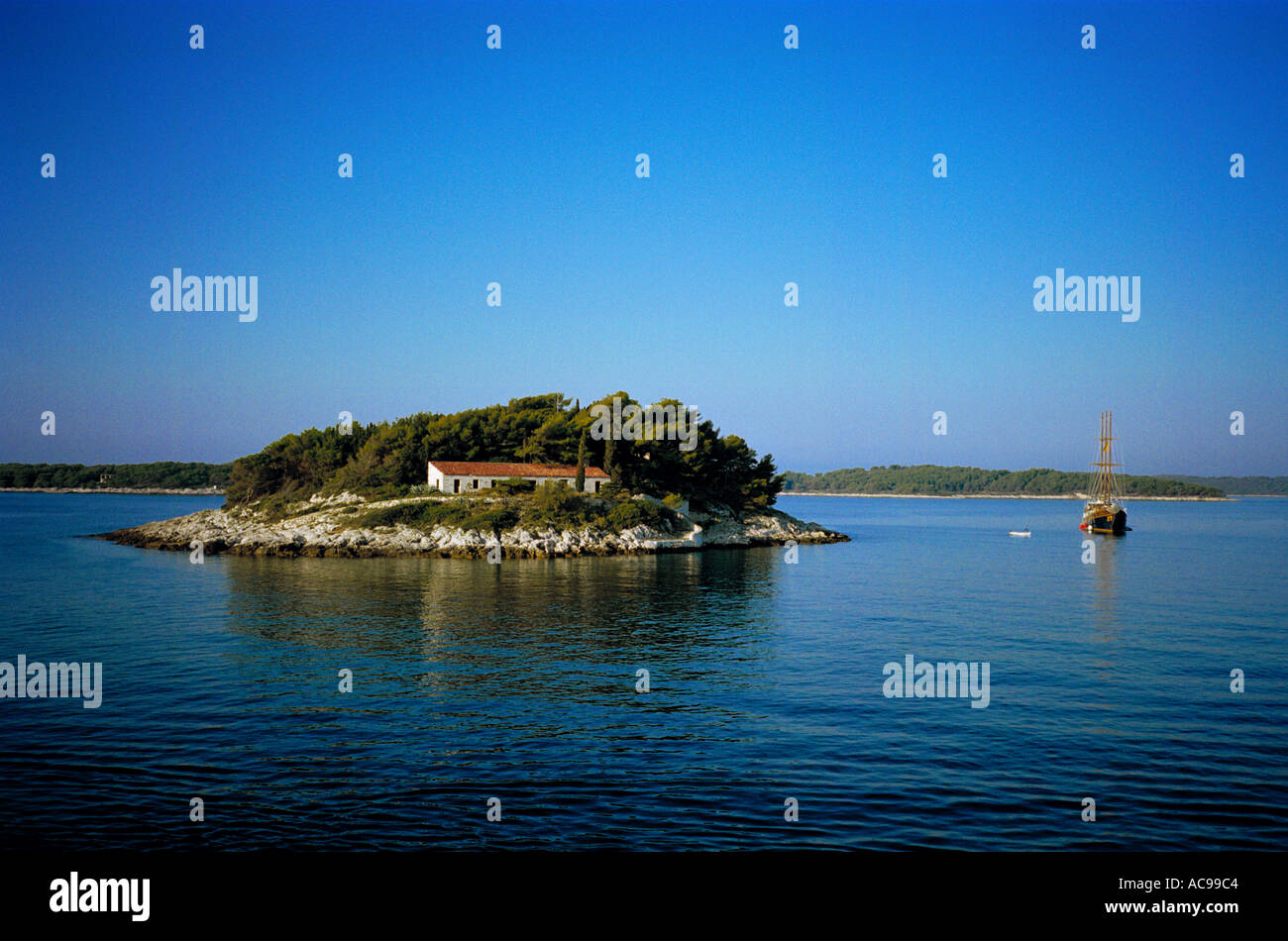 Ein Schoner liegt die kleine Insel Jerolim in der Nähe von Hvar aus der dalmatinischen Küste von Kroatien, in die lebendige Blau von einem ruhigen Morgen Stockfoto