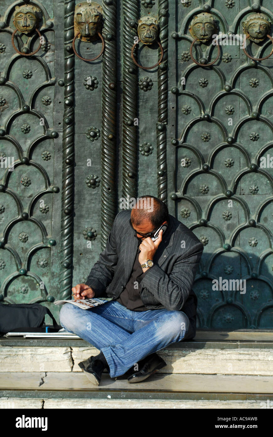 Mann saß mit Telefon im Eingang zum St. Marks Basilika Venedig Italien Stockfoto
