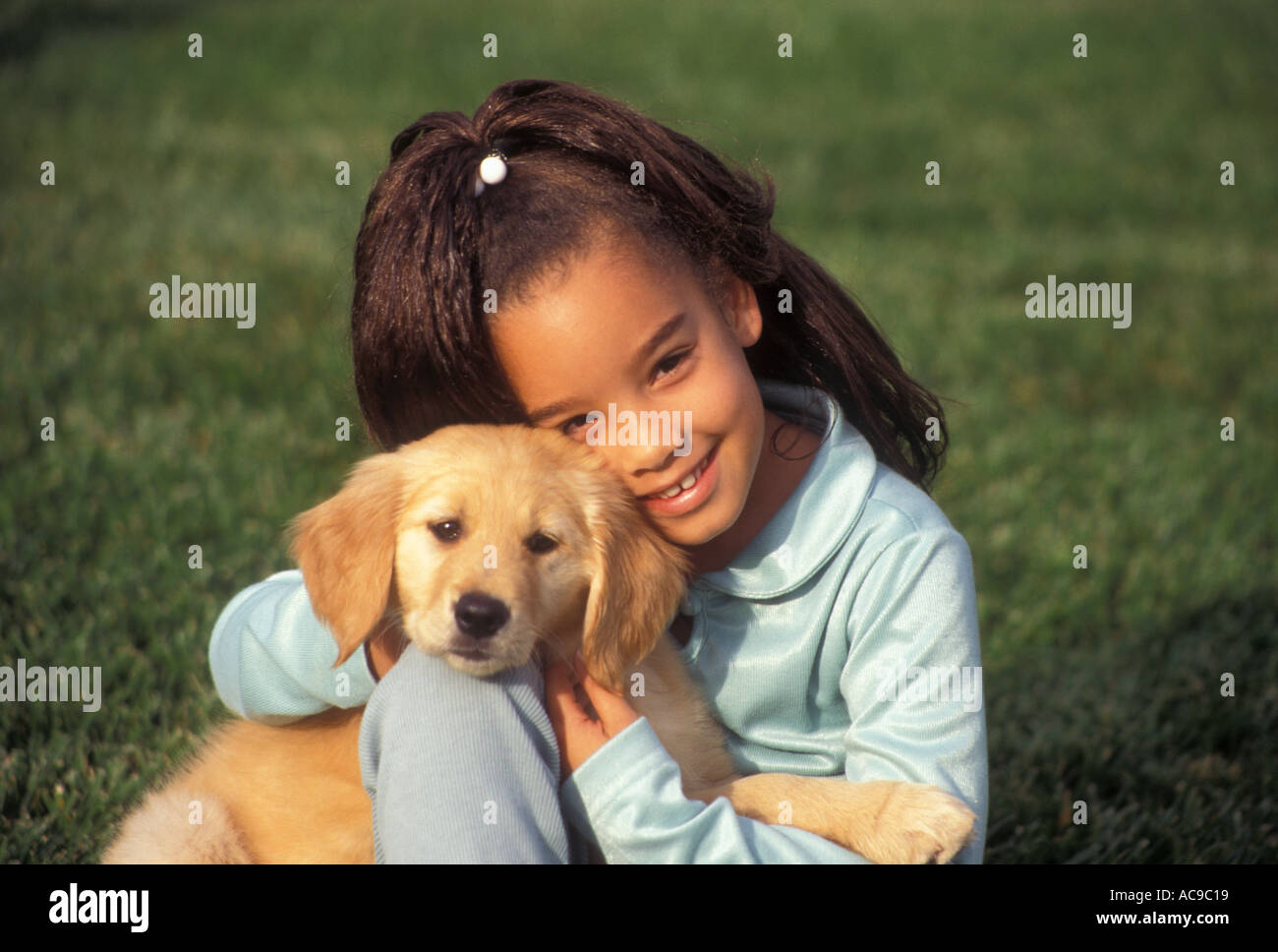 Eine junge ethnische multikulturellen rassisch gemischten Rassenmischung Mädchen 7-9 Jahre altes Kind spielen spielt Welpen golden Welpen POV Myrleen Pearson. ...... Ferguson Cate Stockfoto