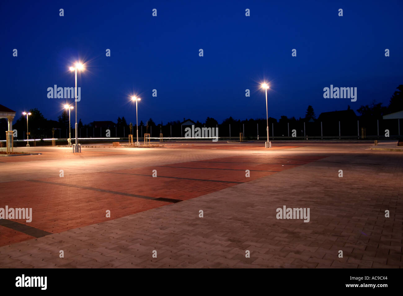 Verlassener Parkplatz, beleuchtet von Straßenlaternen in der Dämmerung. Stockfoto