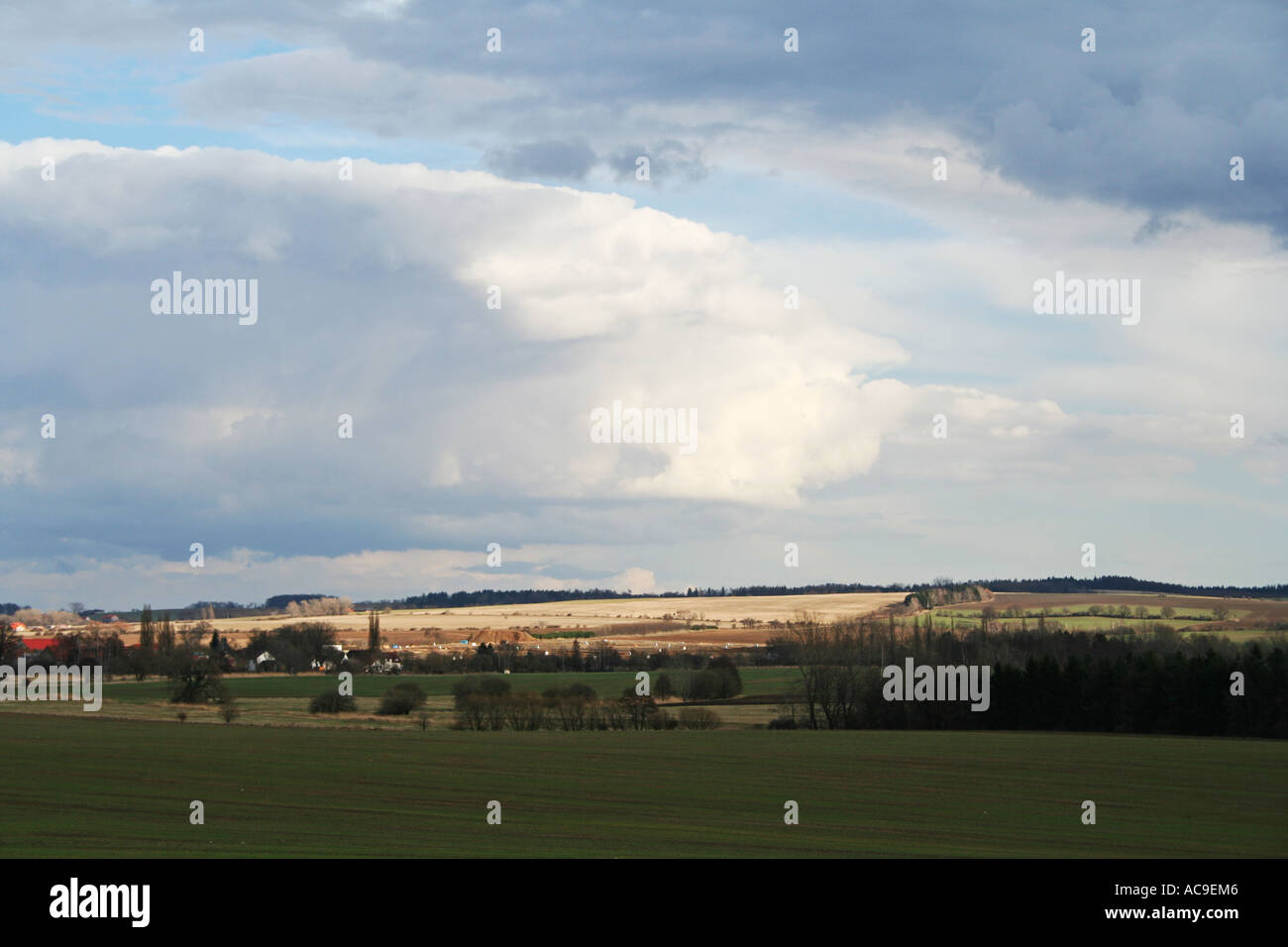 Weitläufige ländliche Landschaft unter bewölktem Himmel mit Feldern und weit entfernten Bäumen. Eine Mischung aus Ruhe und landwirtschaftlicher Landschaft. Stockfoto
