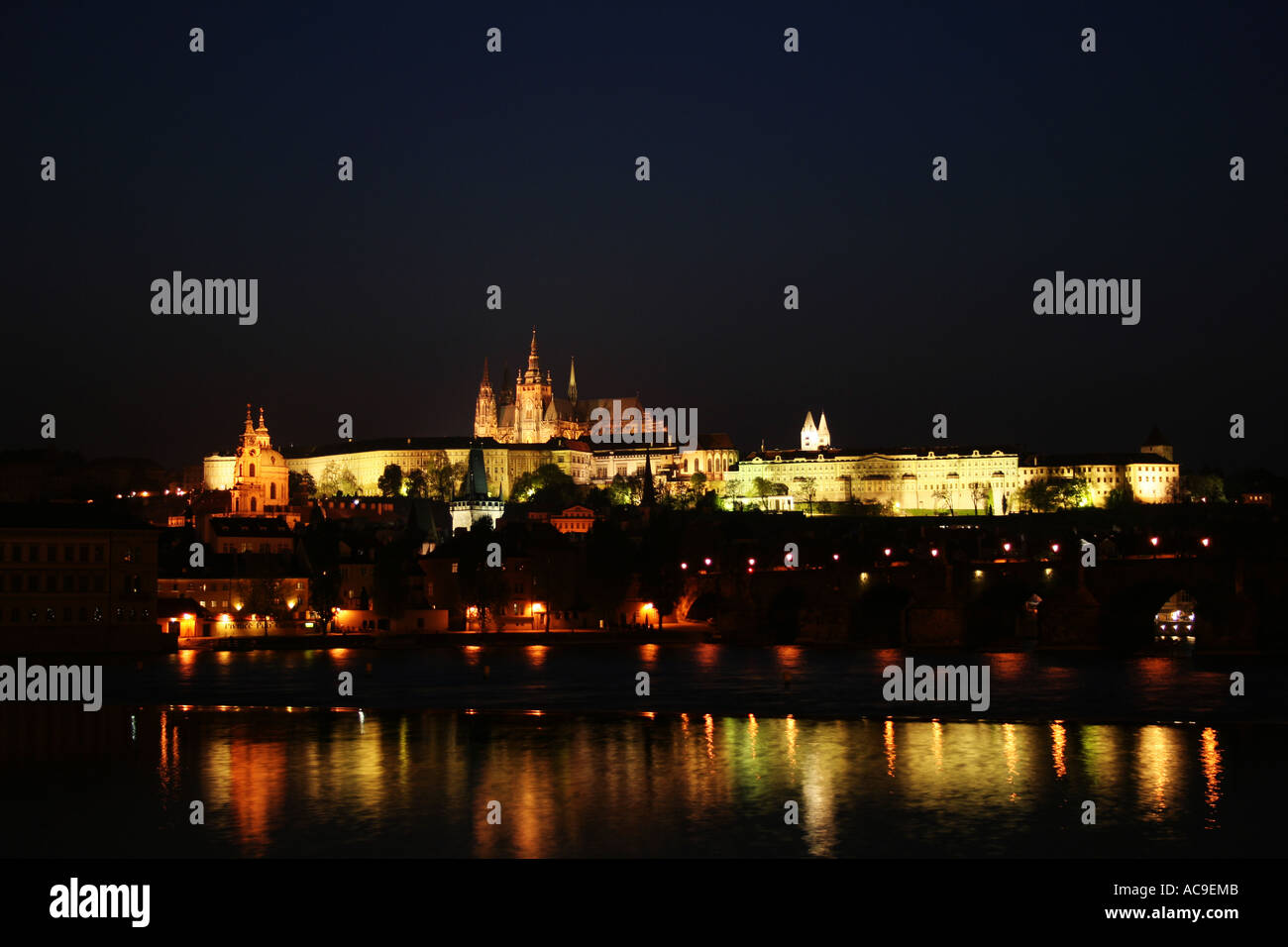 Die Prager Burg ist bei Nacht zu sehen, Moldau und Karlsbrücke sind im Vordergrund zu sehen. Stockfoto