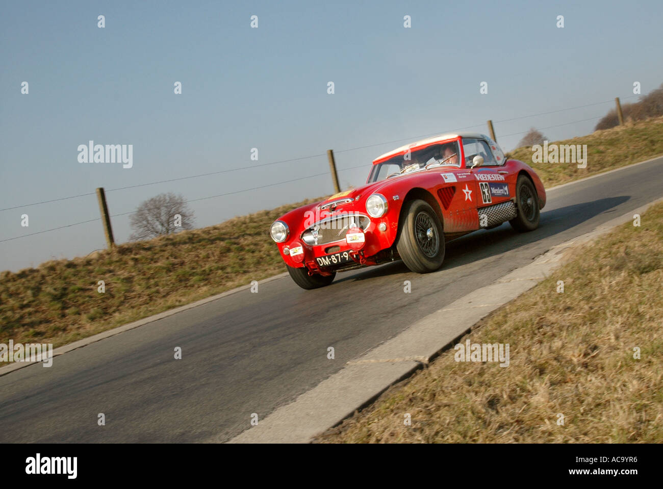 Dreiviertel Vorderansicht des roten Austin Healey 100/6 Rallye-Auto mit voller Geschwindigkeit auf asphaltierten Landschaft Straße nähert sich Stockfoto