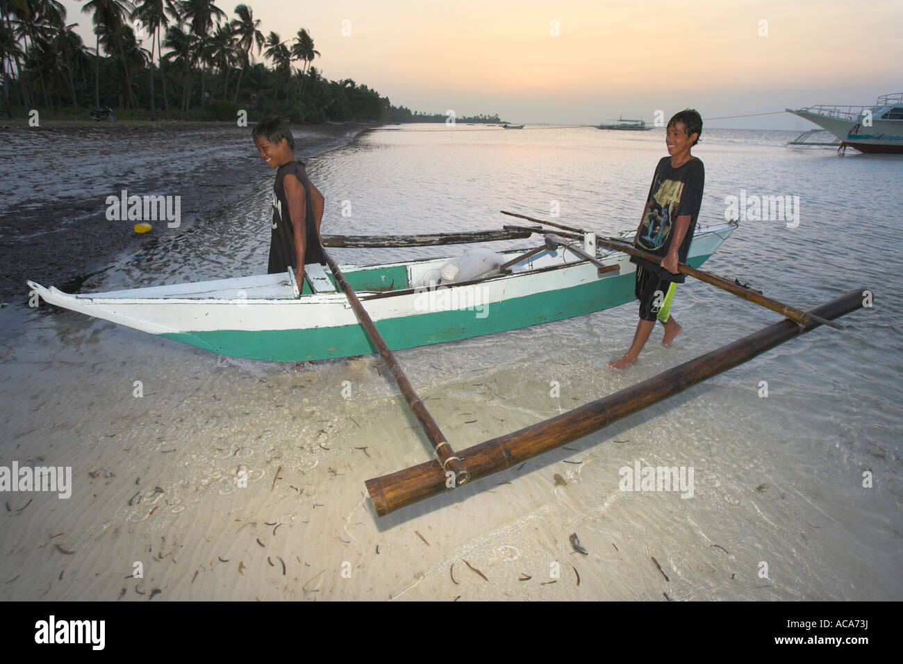 Junge Fischer laden ein Fischerboot mit einem Netz, Philippinen Stockfoto