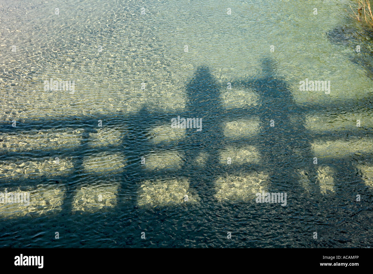 Spiegelbild und Schatten von zwei Personen auf einer Brücke im Wasser Stockfoto