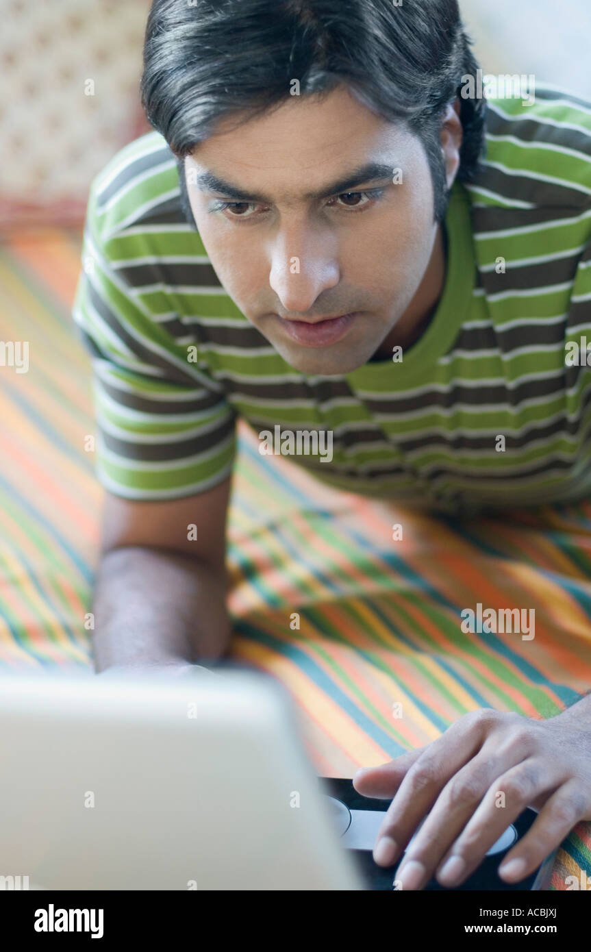 Nahaufnahme eines Mitte erwachsenen Mannes auf einem Bett liegend und mit einem laptop Stockfoto