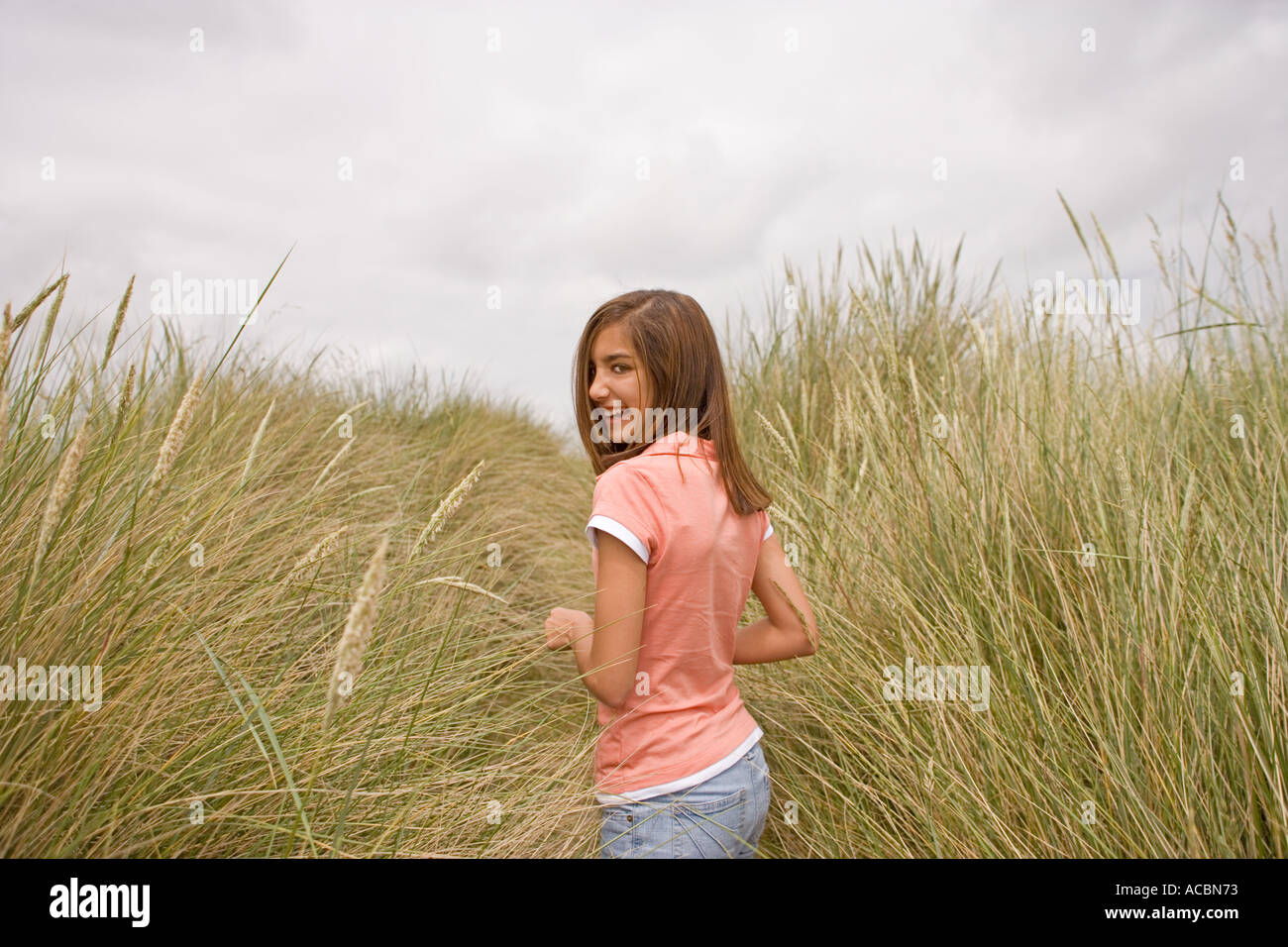 Teenager-Mädchen zu Fuß durch Dünengebieten Grass auf Sanddünen UK Norfolk Stockfoto