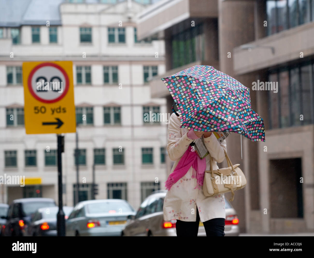 Windigen und regnerischen Wetter in London, kämpft eine Frau den wind Stockfoto