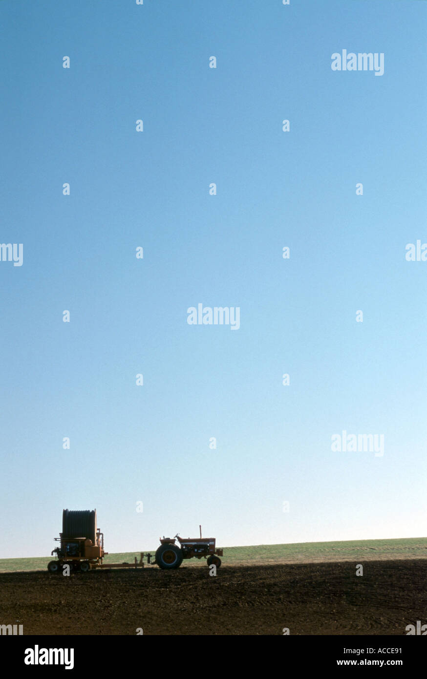 Silhouette der Traktor Abschleppen Beregnungs-und Bewässerungstechnik gegen blauen Himmel ähnliches Bild ACCE92 Stockfoto