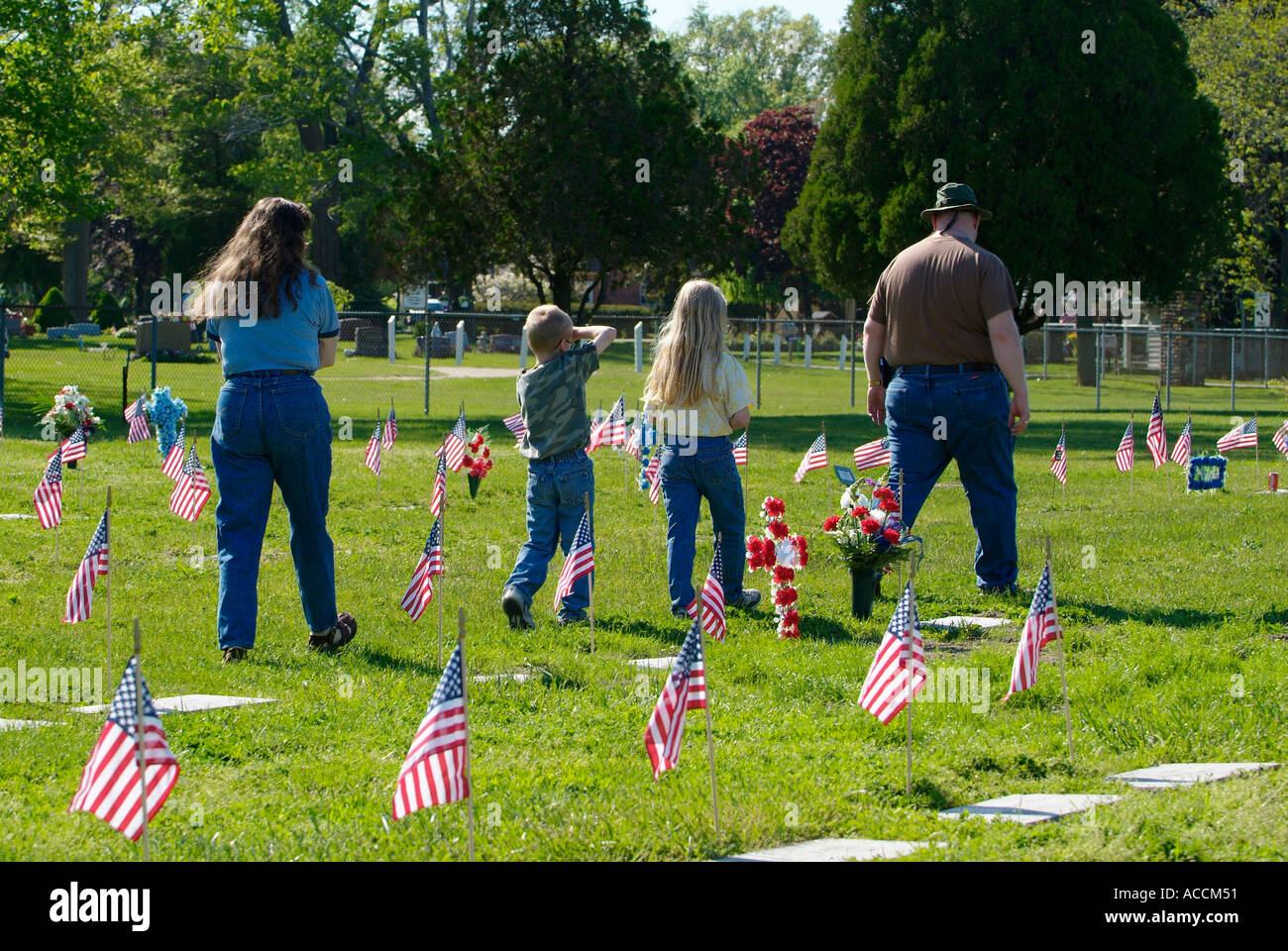 Familie besucht Friedhof am Memorial Day, Flaggen auf Gräbern zu platzieren Stockfoto
