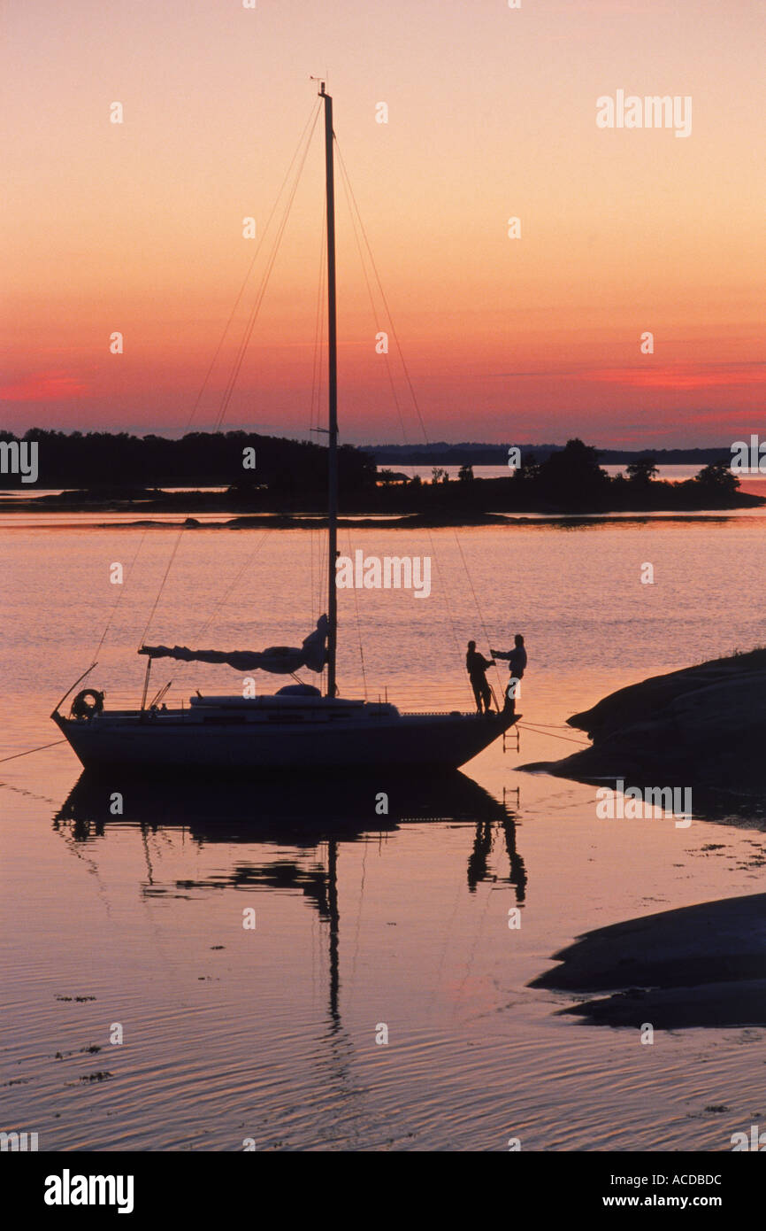 Paar auf Segelboot bei Sonnenuntergang vor kleinen Stockholmer Schären-Insel in Ostsee verankert Stockfoto