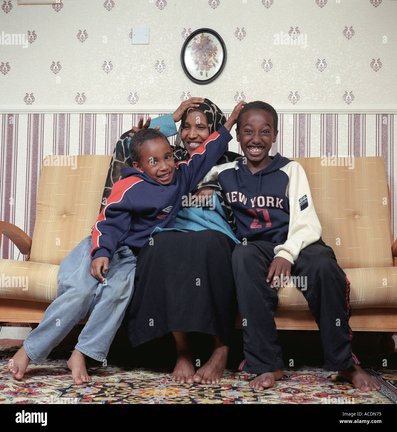 Eine alleinerziehende Mutter aus Somalia mit zwei ihrer Kinder in ihrem Wohnzimmer, UK. Stockfoto