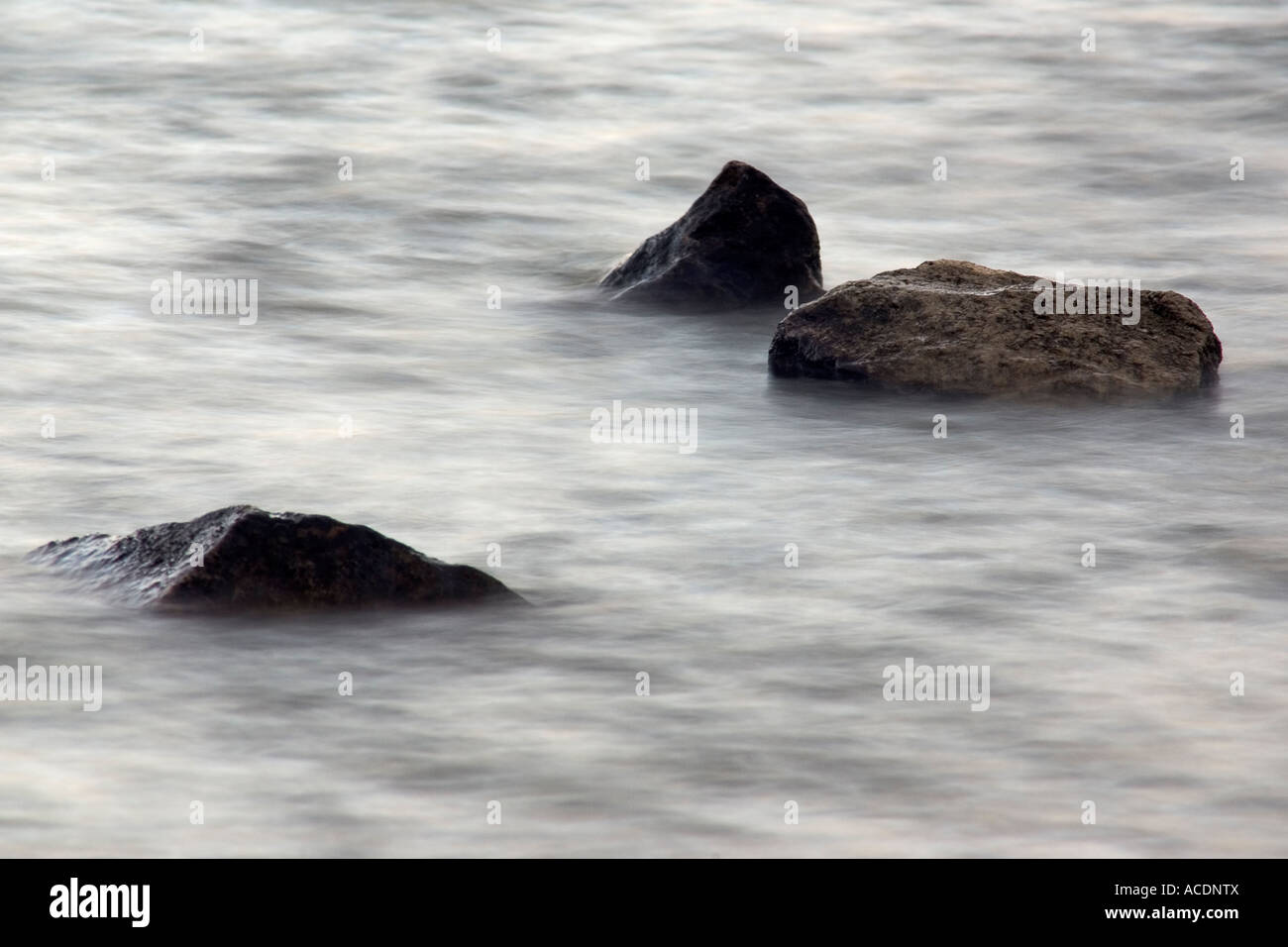 Landschaft / horizontale Foto verwackelt Wasser etwa drei Granitfelsen, die obere ähnelt einen Haie Fin Stockfoto