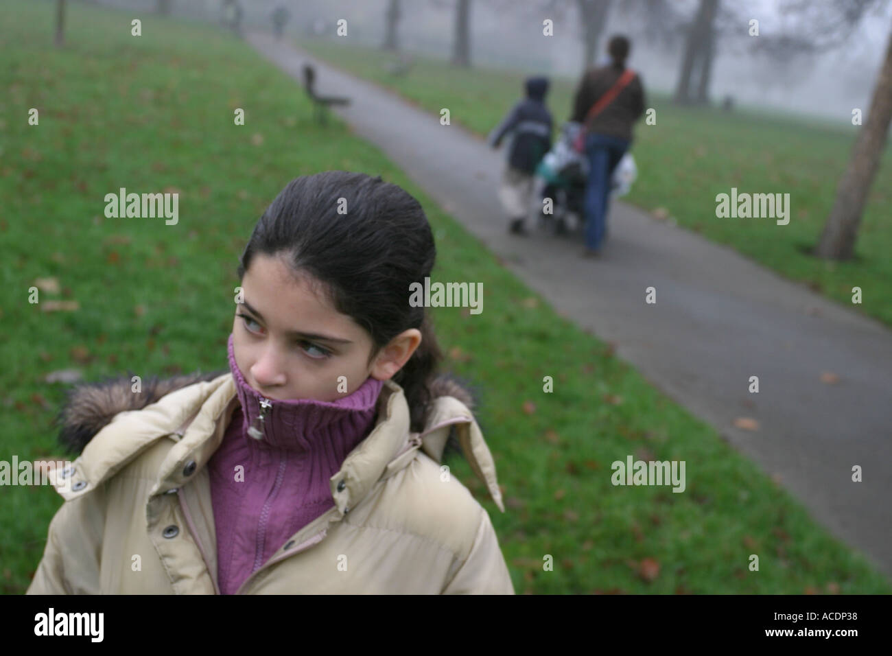 Ein 9 Jahre altes Mädchen auf dem Weg zur Schule mit ihrer Mutter und Geschwister im Hintergrund, Clissold Park, Stoke Newington, London. Stockfoto