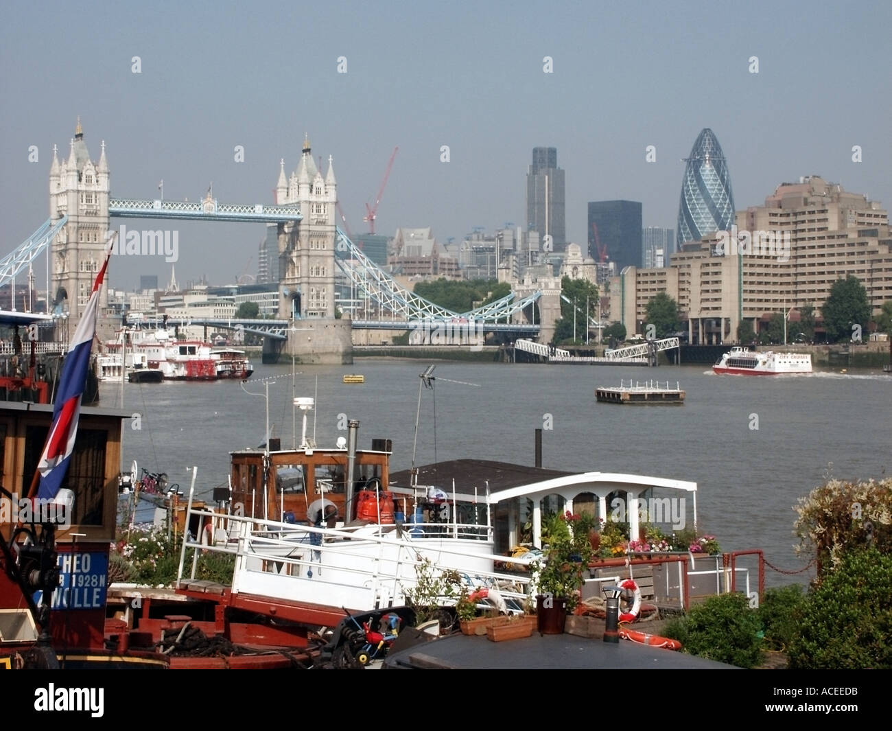 Thames Seite Promenade in der Nähe von Butlers Wharf mit der Londoner Skyline einschließlich Neubau Gherkin Büro- und Hausboote Stockfoto