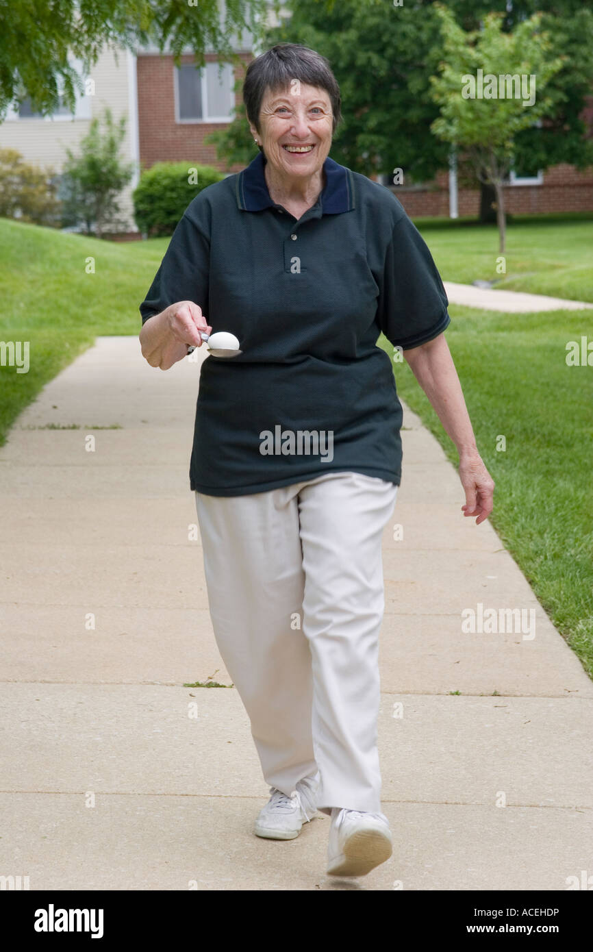Ältere Menschen im Ruhestand, Frau Alter von 77 Jahren im Wettbewerb mit einem Ei und Löffel Rennen Stockfoto