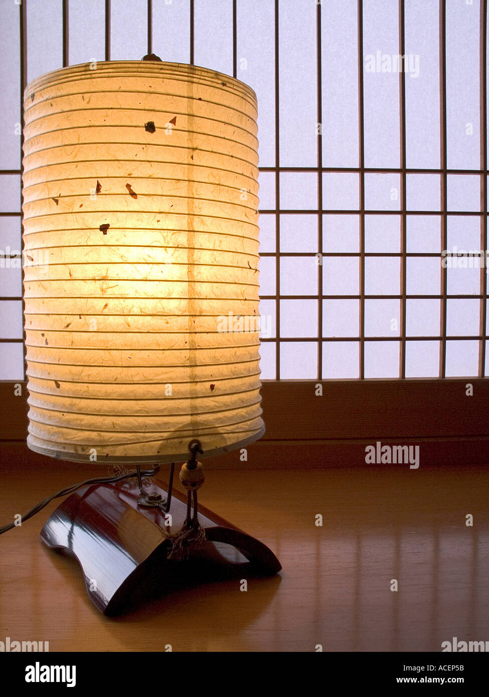 Das künstliche Licht der leuchtenden Bodenlaterne aus Papier steht im Kontrast zum natürlichen Licht des Shoji-Bildschirms aus Papier für ein japanisches ästhetisches Bild oder Konzept Japans. Stockfoto