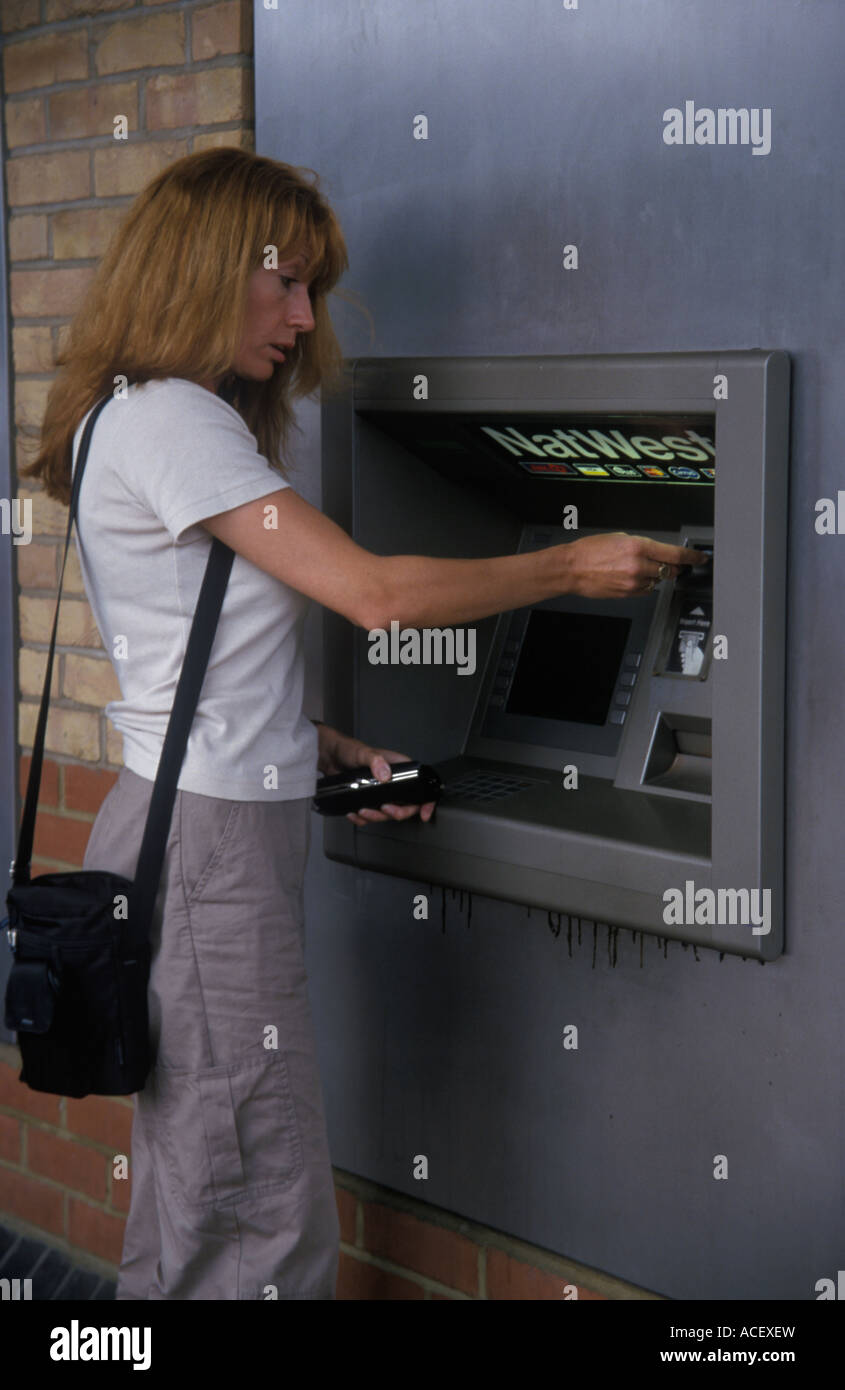 Frau immer Geld aus einem Loch in der Wand Stockfoto