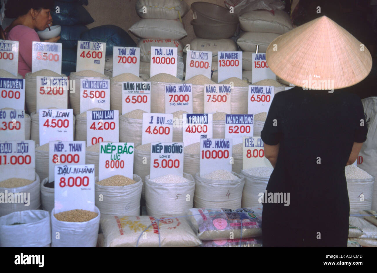 Hanoi vietnamesische Frau mit Strohhut vor Reis-shop Stockfoto