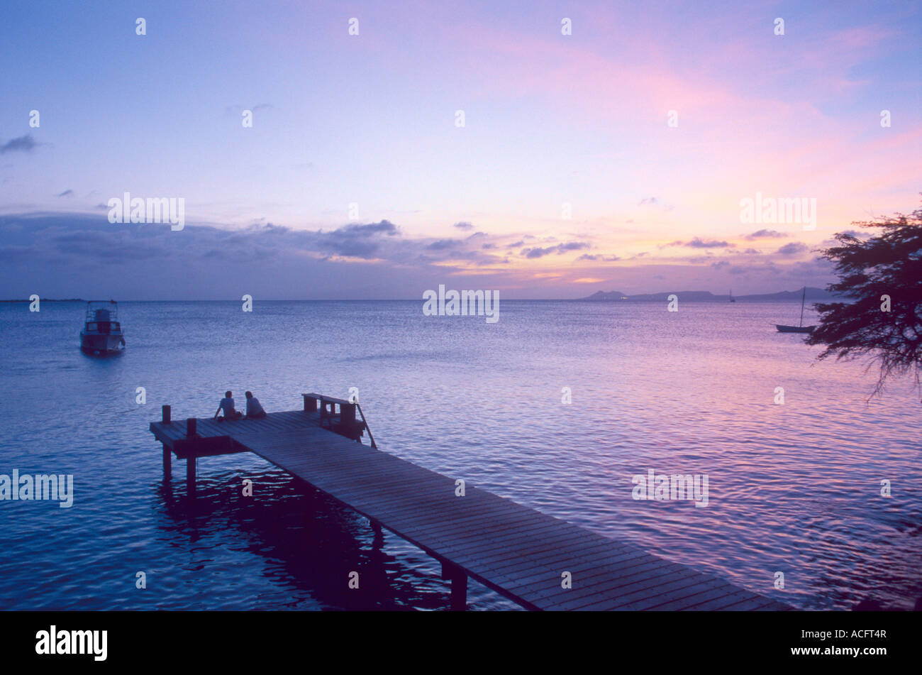 Paar sitzt zusammen Romanticaly das Ende der großen Dock bei Sonnenuntergang. Nicht Modell veröffentlicht Bonaire, Niederländische Antillen Stockfoto