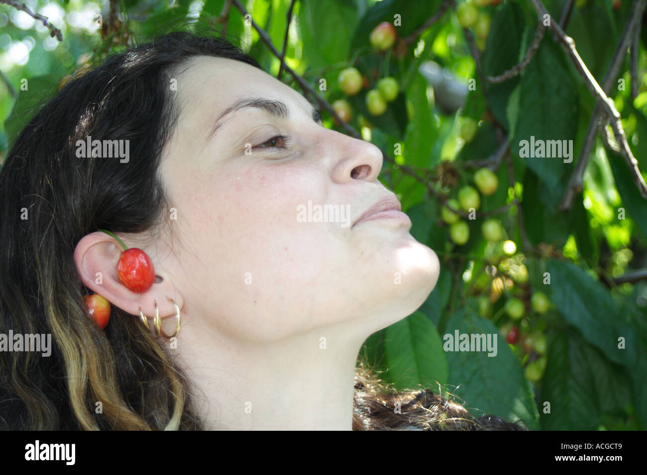 Junge Frau lächelt und paar Kirsche auf ihr Ohr tragen Stockfoto