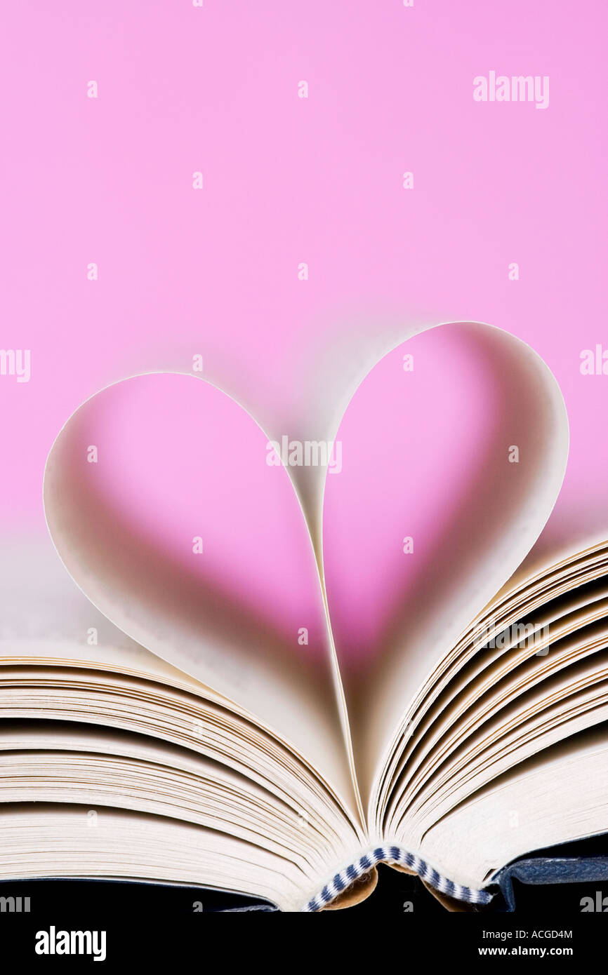 Herzform aus Buchseiten vor einem rosa Hintergrund gemacht Stockfoto