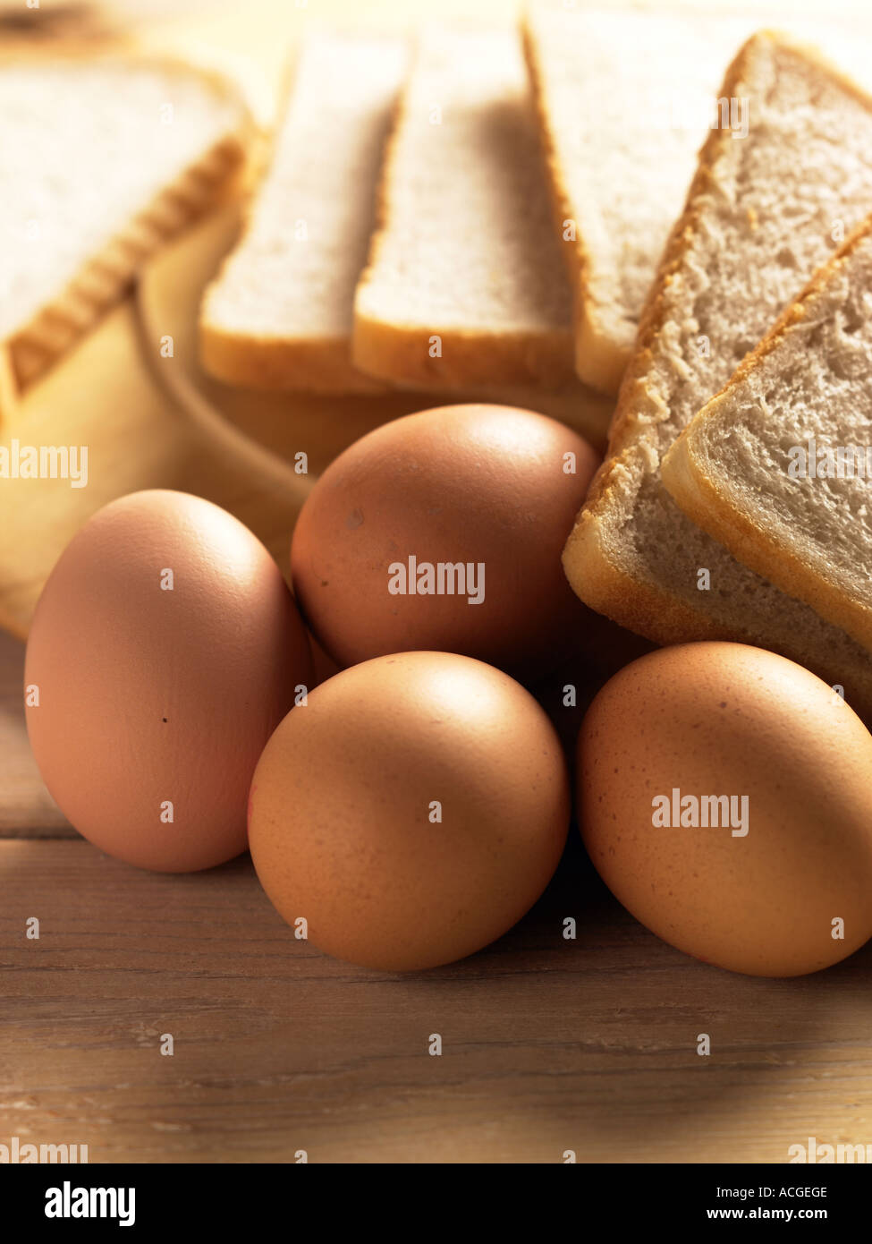 Porträtaufnahme von vier Eiern mit Scheiben von Weißbrot Schuss auf Lattenrost Holztisch mit warmen sonnigen Beleuchtung Stockfoto