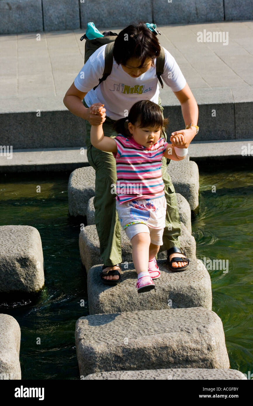 Koreanische Mutter hilft Tochter über Cheonggyecheon oder Cheonggye Stream Seoul Südkorea Stockfoto