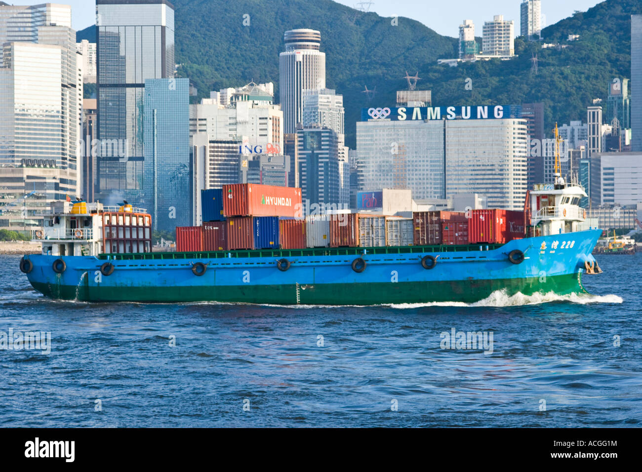 Schiff, beladen mit Containern im Victoria Harbour mit Skyline Hong Kong SAR Stockfoto