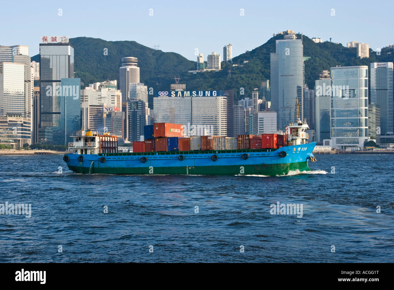 Schiff, beladen mit Containern im Victoria Harbour mit Skyline Hong Kong SAR Stockfoto
