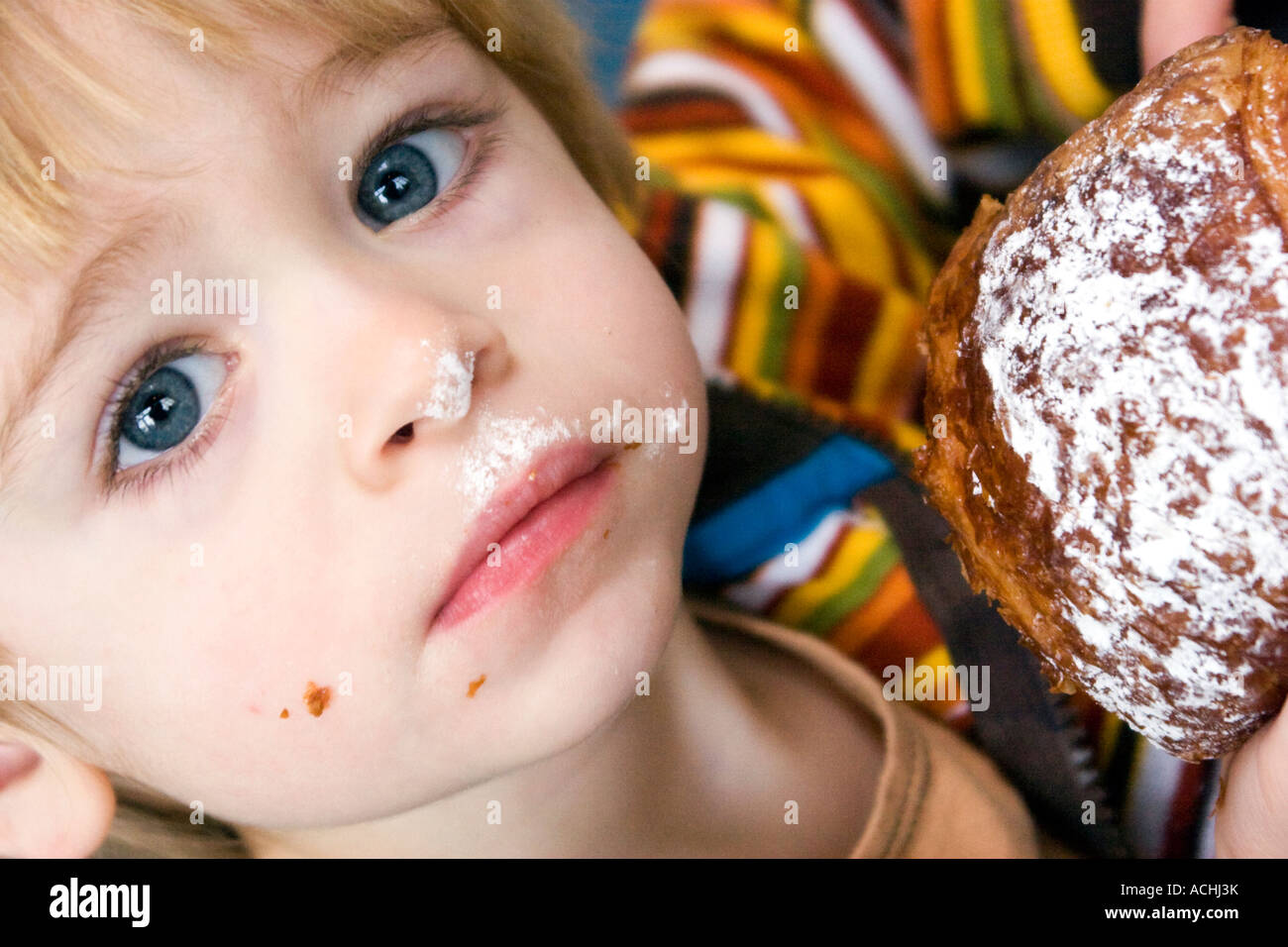 Nahaufnahme der mit weit aufgerissenen Augen kleiner Junge eine Croissant zu essen. Stockfoto