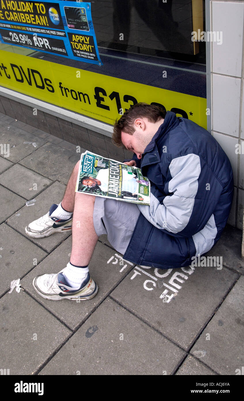 Ein Big Issue Verkäufer schlafend auf seinem Stellplatz außerhalb einen Plattenladen HMV in Western Road Brighton Stockfoto