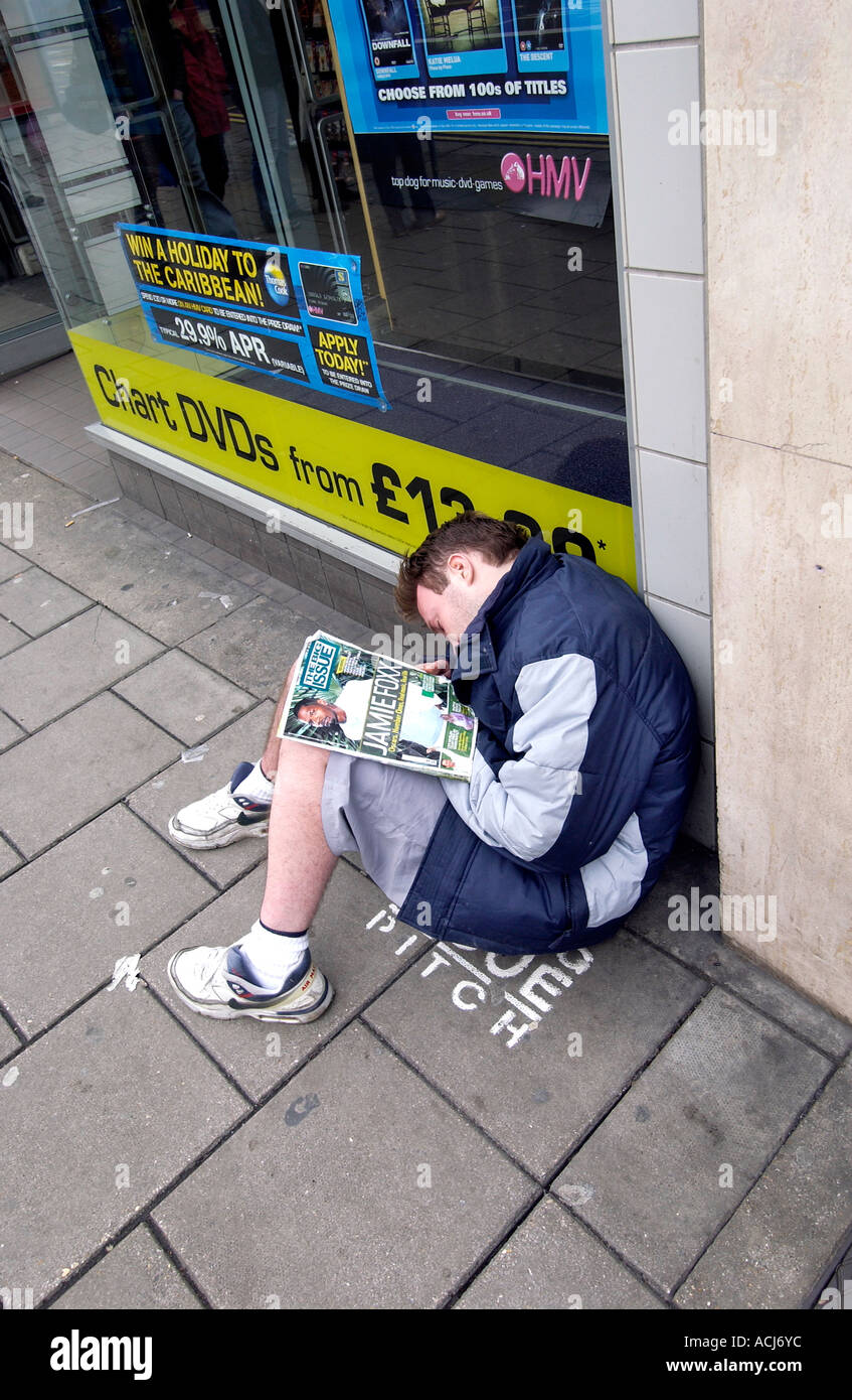 Ein Big Issue Verkäufer schlafend auf seinem Stellplatz außerhalb einen Plattenladen HMV in Western Road Brighton Stockfoto