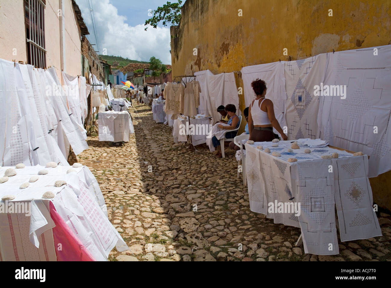 Frau betrachten Spitze Bettwäsche und Tischdecken zum Verkauf zu einem Straßenmarkt, Trinidad, Kuba. Stockfoto