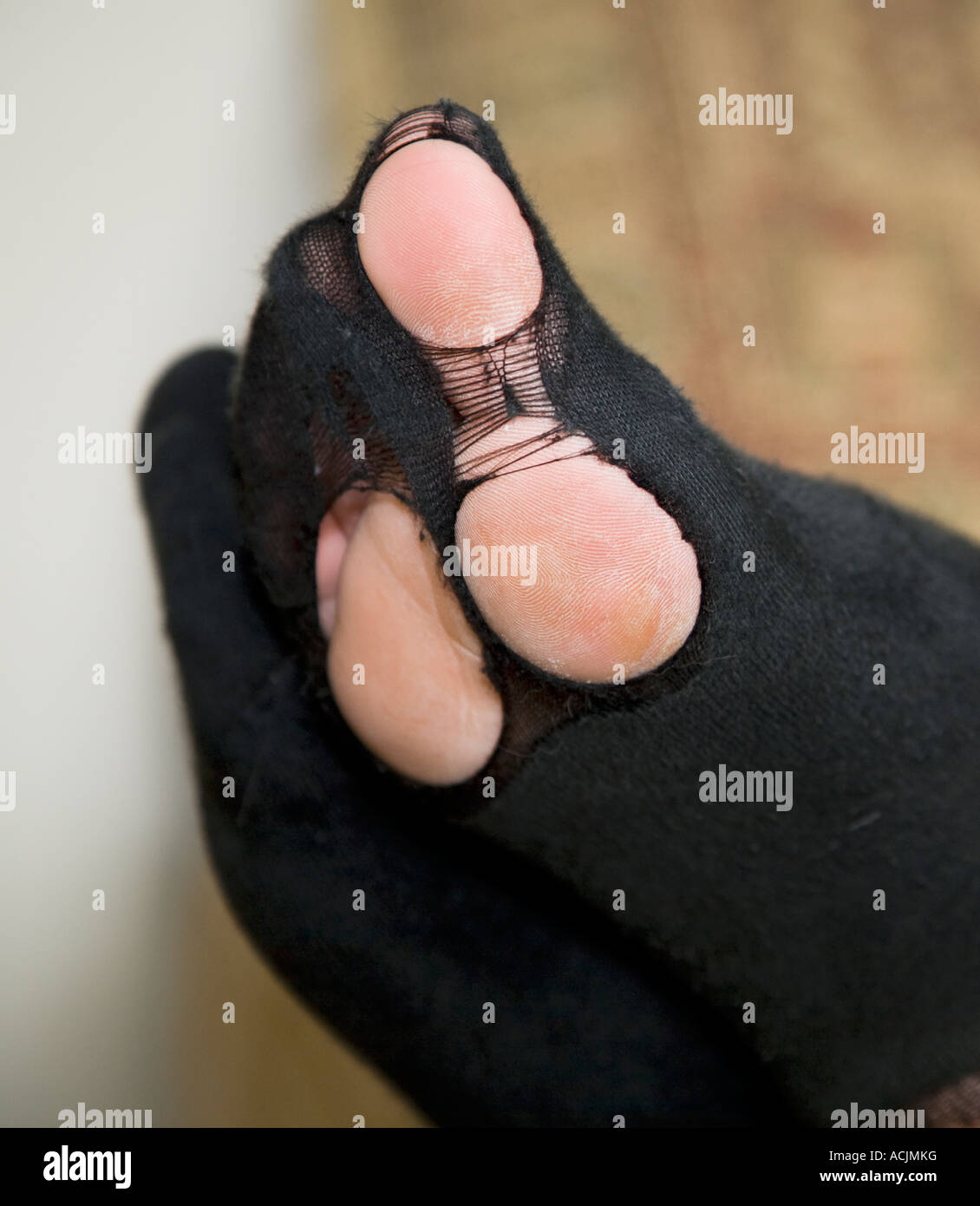 GETRAGENE SOCKEN MIT FÜßEN UND ZEHEN ZEIGEN SICH DURCH DIE LÖCHER Stockfoto