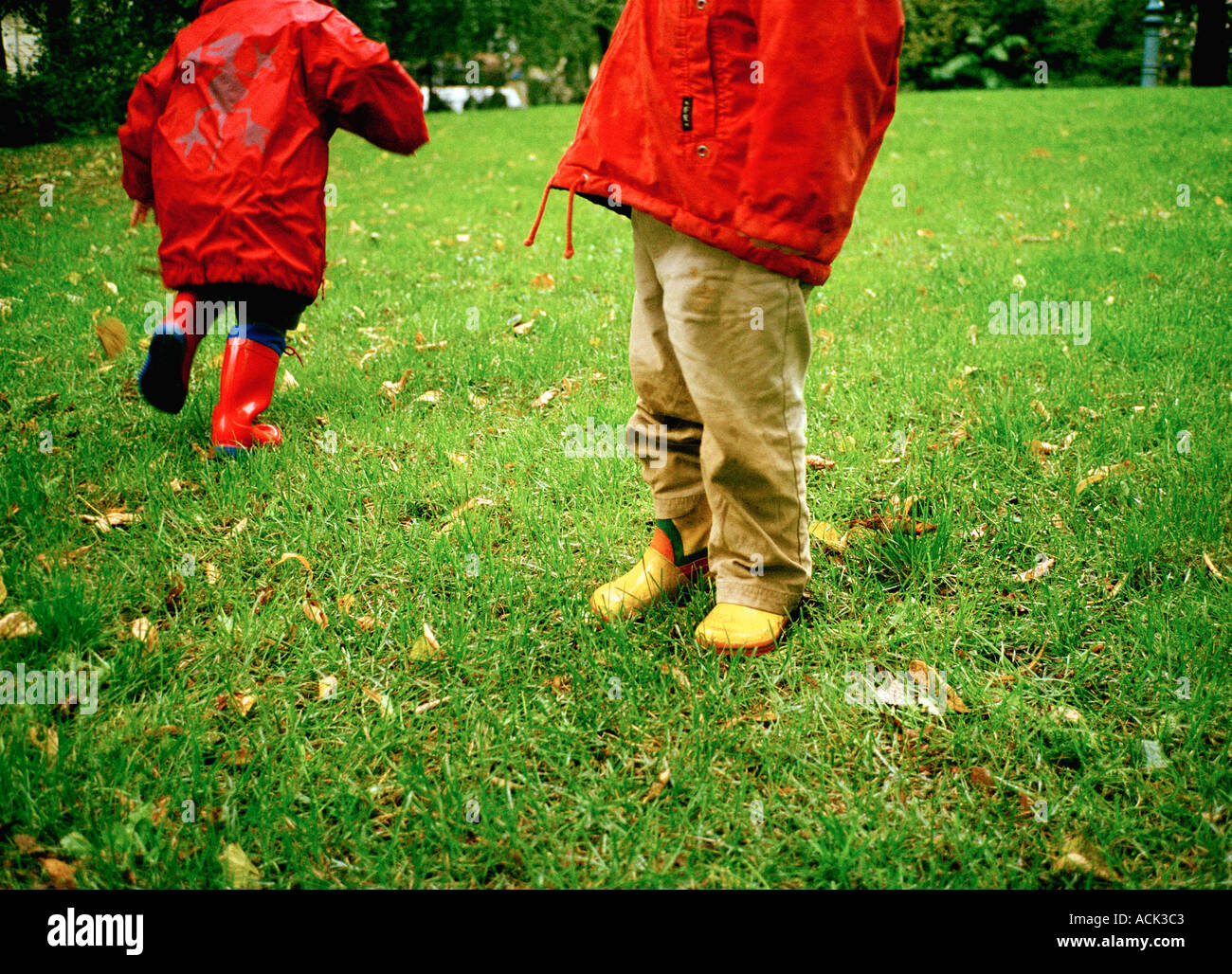 Kinder s Regen Stiefel auf nassem Rasen Stockfoto
