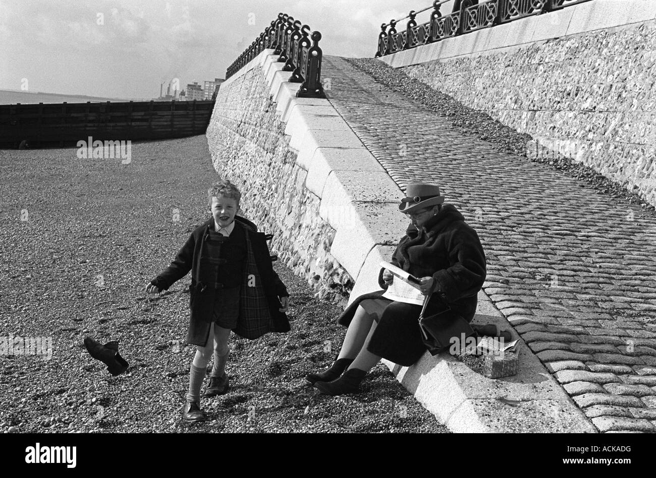 Brighton Beach Sussex England 1970. Der kleine Junge schwingt seinen Schuh an den Schnürsenkeln mit seiner Großmutter, die sich um ihn handelt. HOMER SYKES AUS DEN 1970ER JAHREN Stockfoto