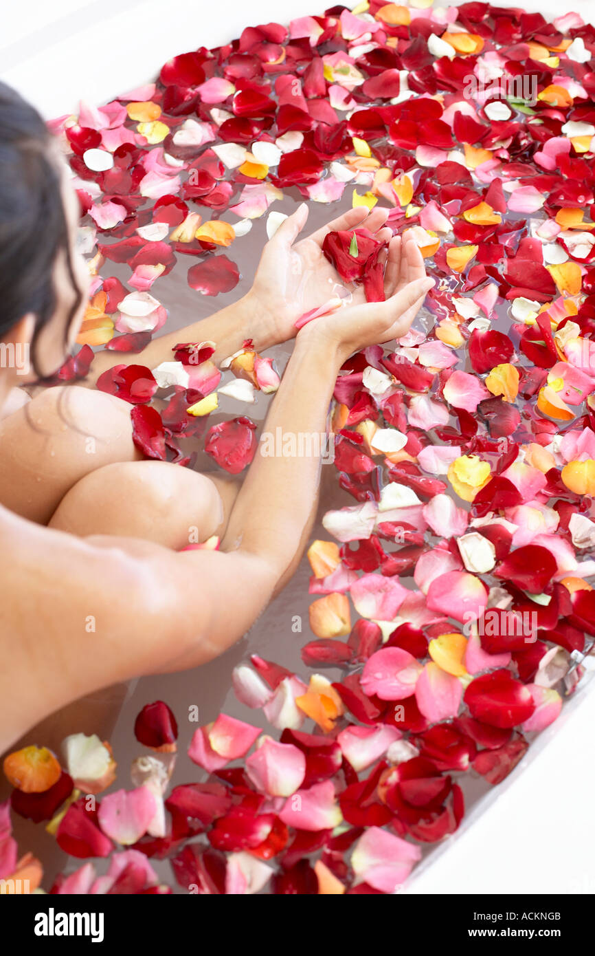 Junge Frau in einer Badewanne gefüllt mit Rosenblättern Stockfoto