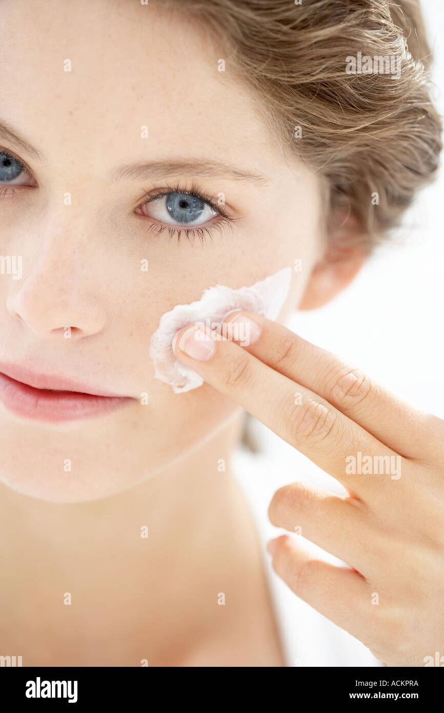 Junge Frau Anwendung Creme im Gesicht Stockfoto