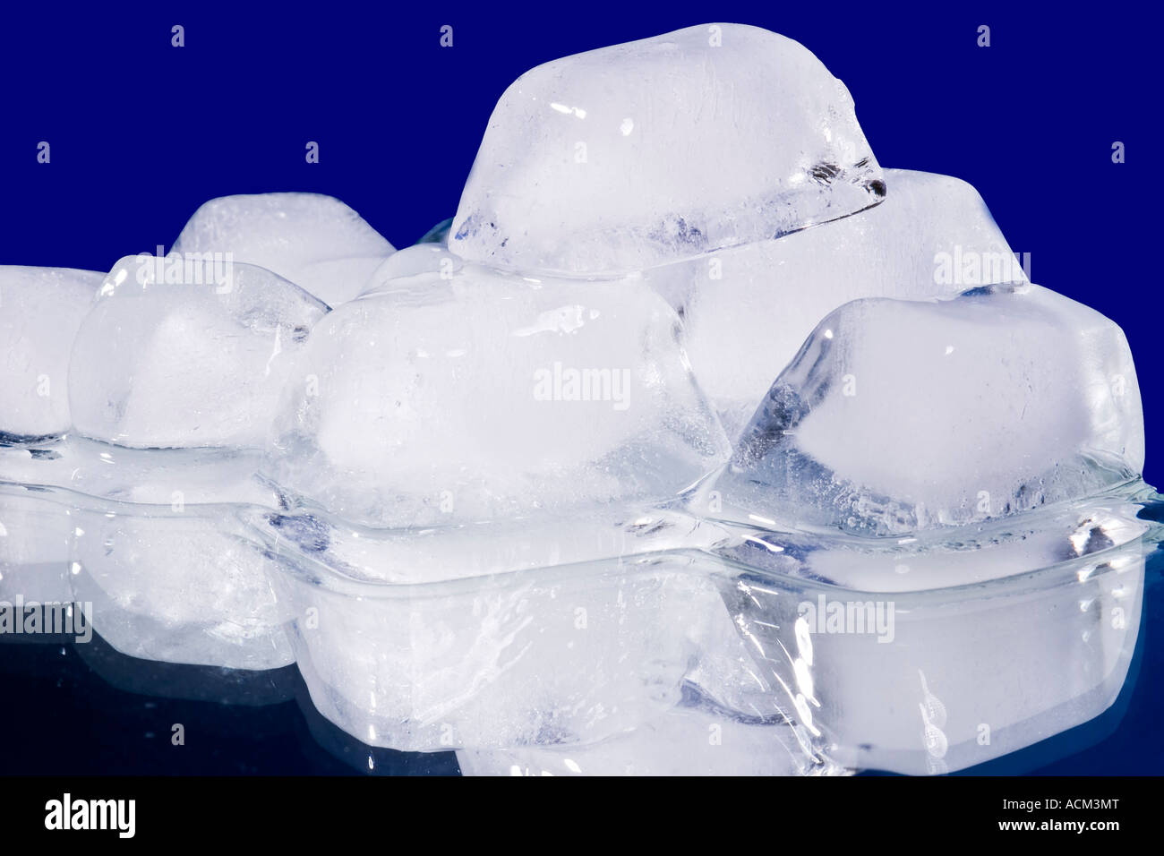 Schmelzende Eiswürfel mit Wasser fällt auf einen Spiegel - blauem Hintergrund Stockfoto